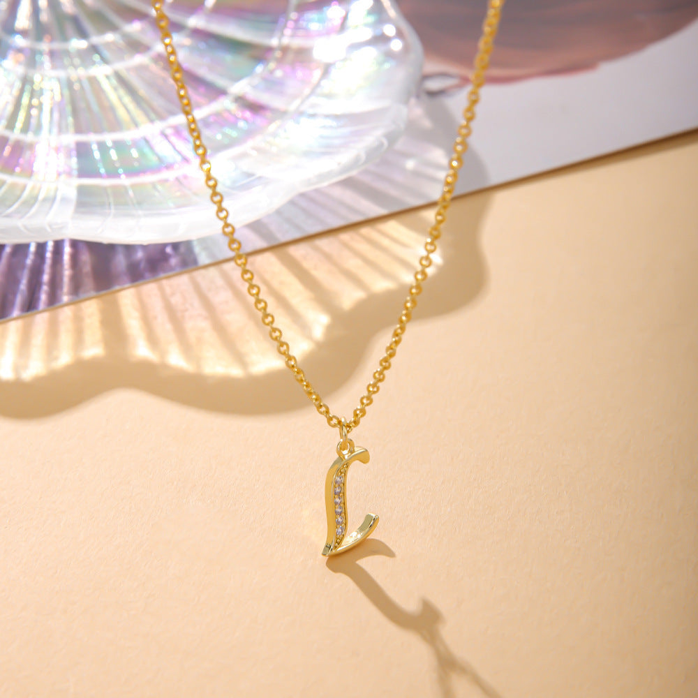 An O-shaped chain necklace from K.Bola, the Fashion English 26 Letters Inlaid Zircon Copper Necklace, is displayed on a beige surface. It features a gold L pendant adorned with small diamonds, set against a stunning multicolored iridescent shell background.